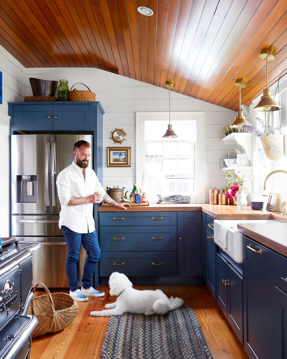 Groggy Anchor Cape Cod Cottage home of steve ballerini and colin bohrer, one of the oldest cape cottages in provincetown, massachusetts cape cod cottage, cape cod style home kitchen wtih tavern flooring, blue cabinets wall color london fog by benjamin moore