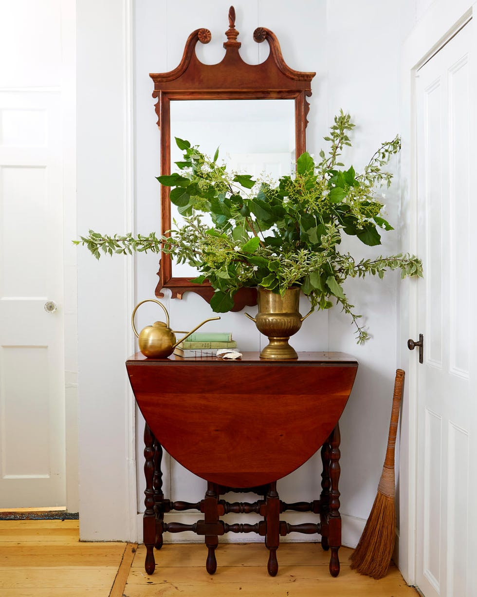a wood table with a brass vase with big branches a wood table with a brass vase with big branches