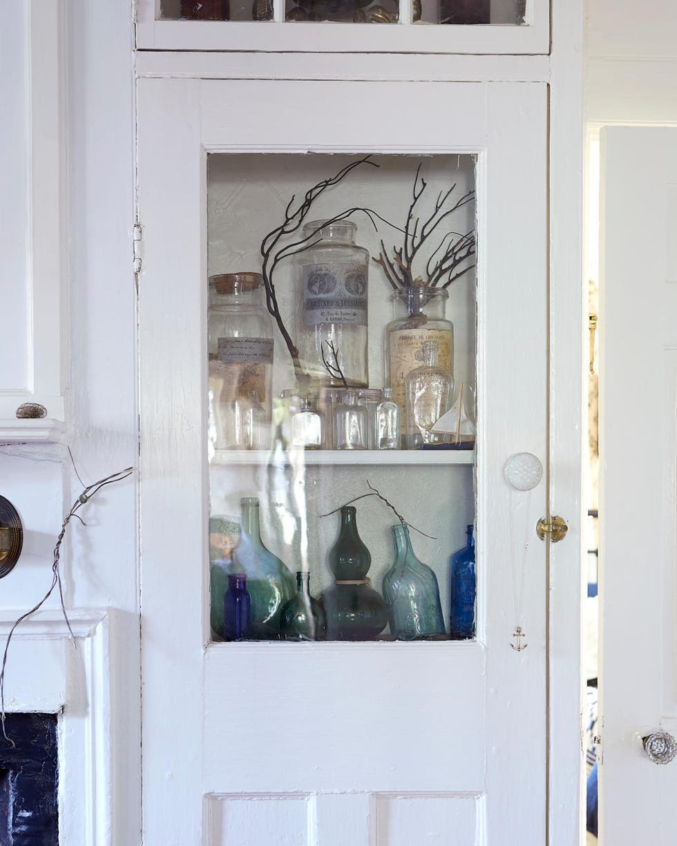 a white cabinet with antique glass bottles a white cabinet with antique glass bottles