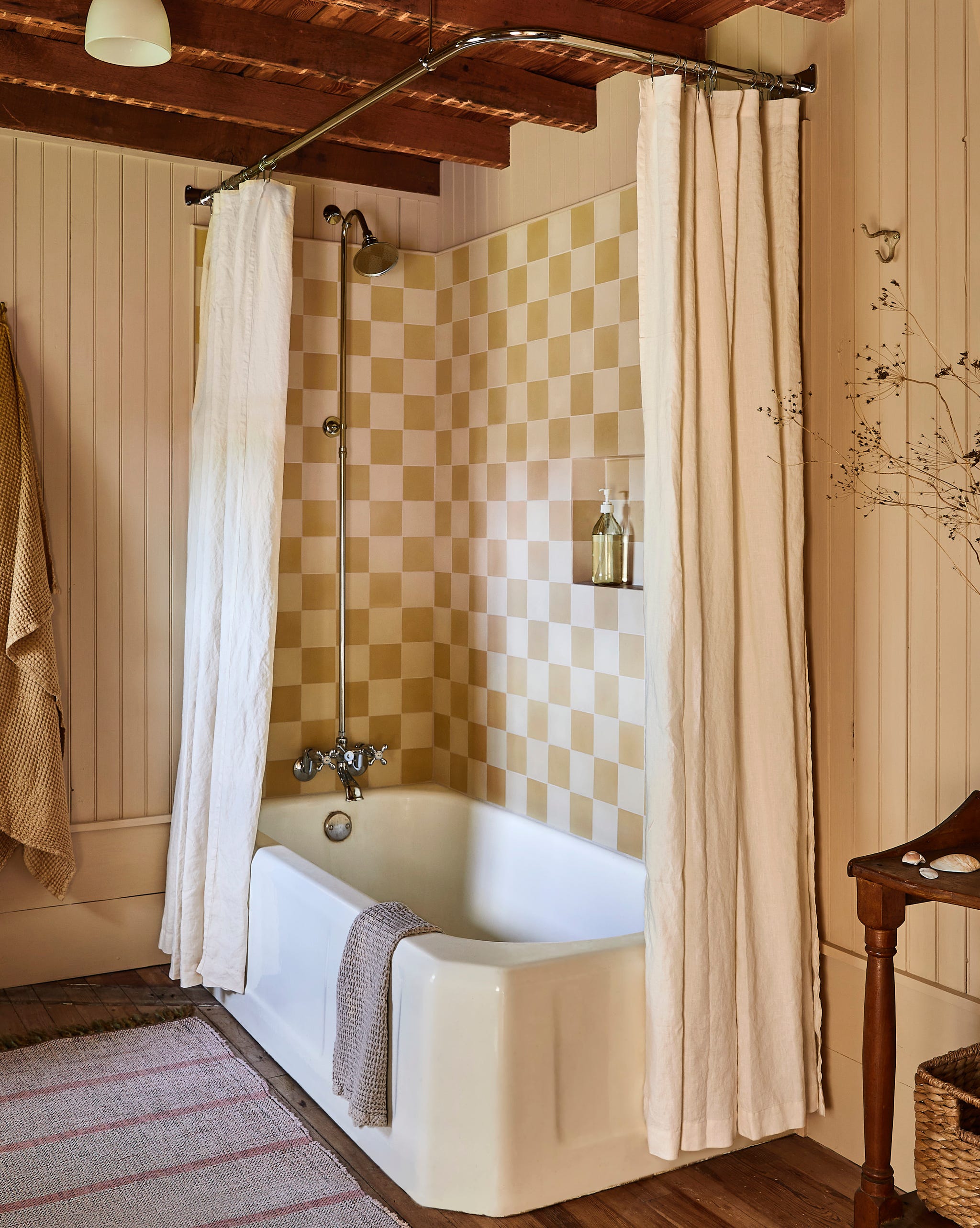 bath tub with checkered tile on wall and neural curtain