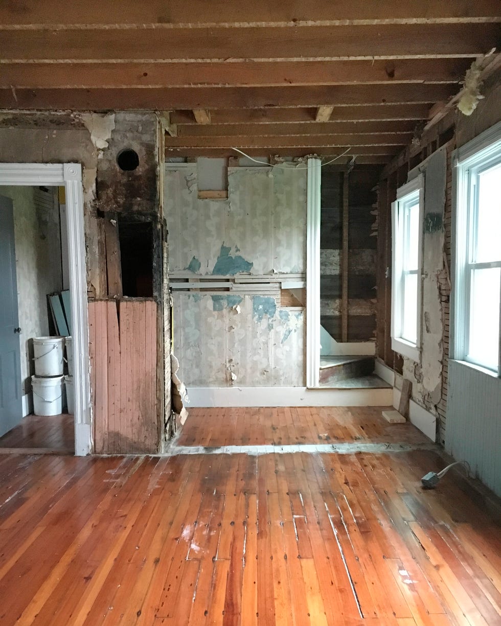 room with wood floors and walls torn out