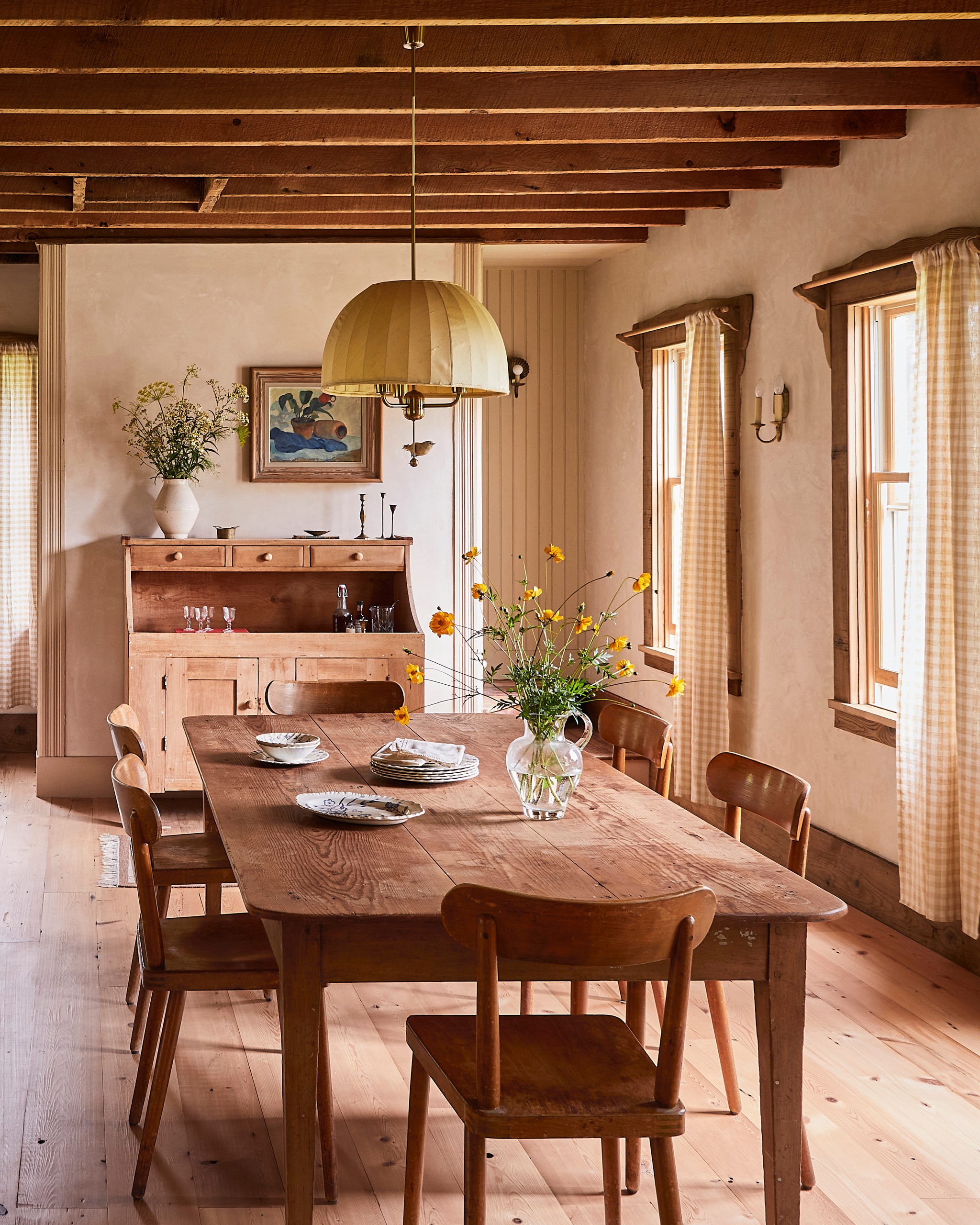 farmhouse dining room with wood floors, wood table and chairs, and gingham curtains