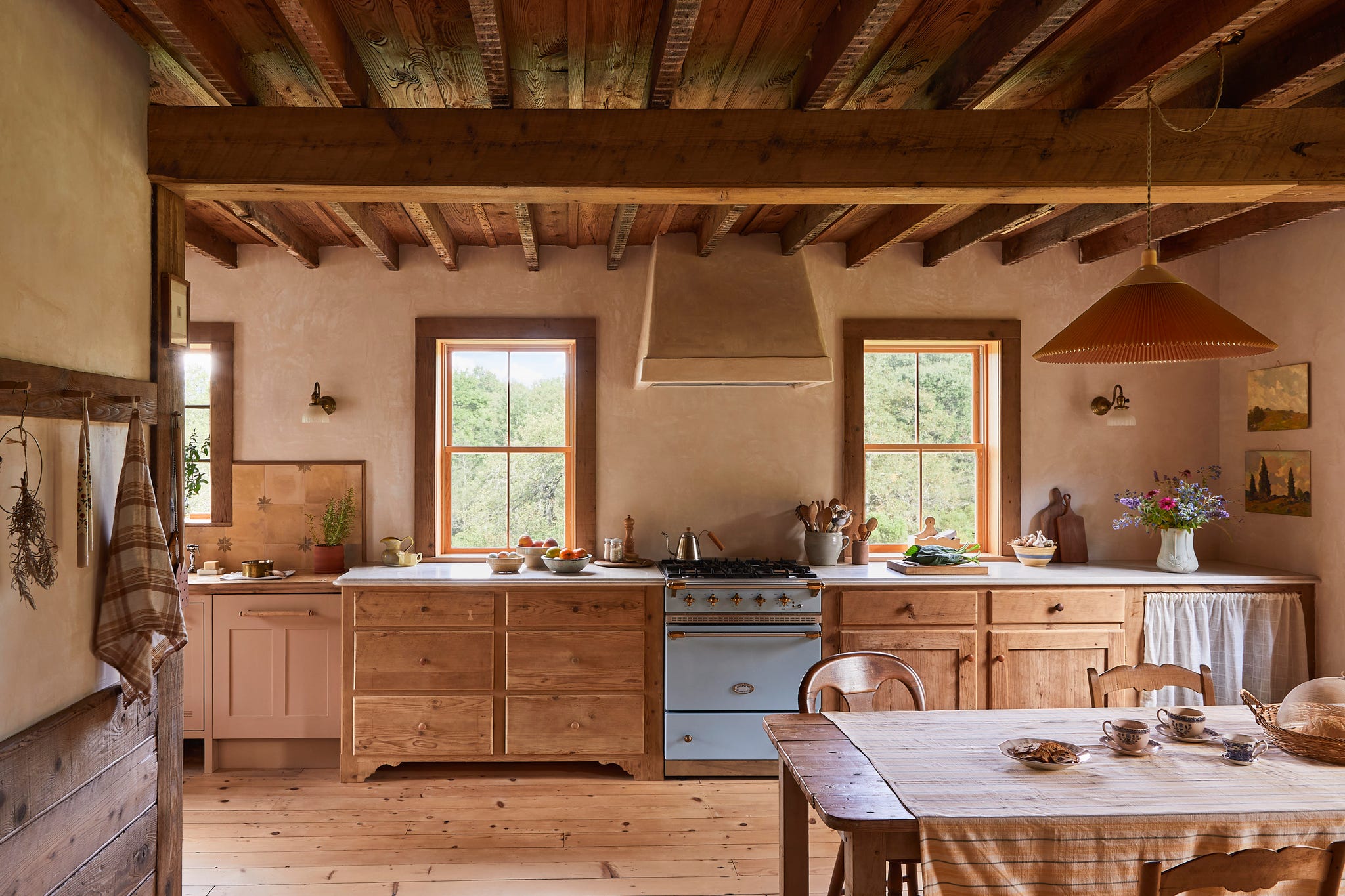 kitchen with wood floors, wood cabinets, blue stove, and wood table