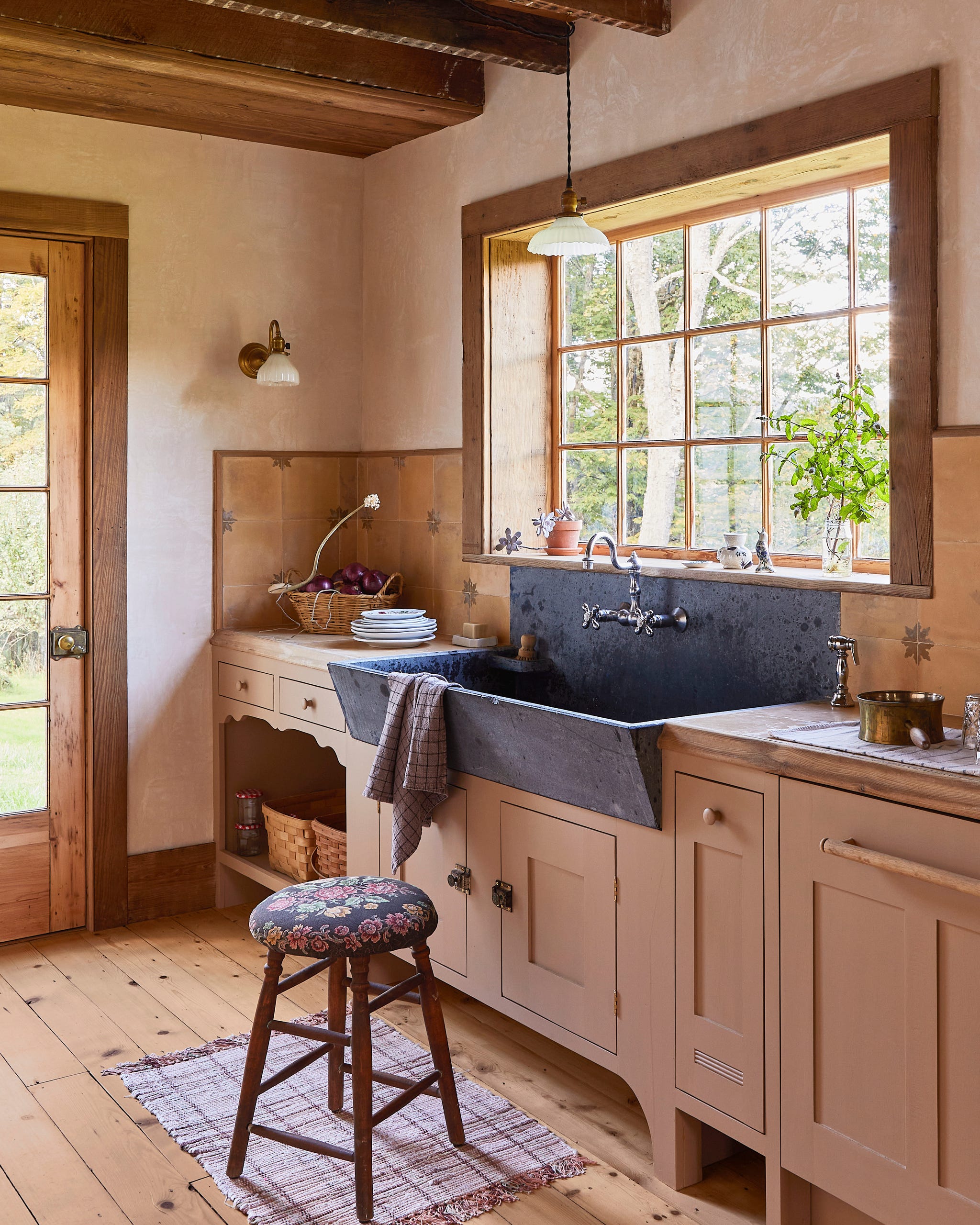 kitchen with painted cabinets, wood floors, and a window above a soapstone sink