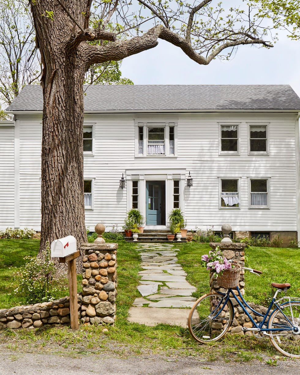 white farmhouse exterior with blue door and bike in front