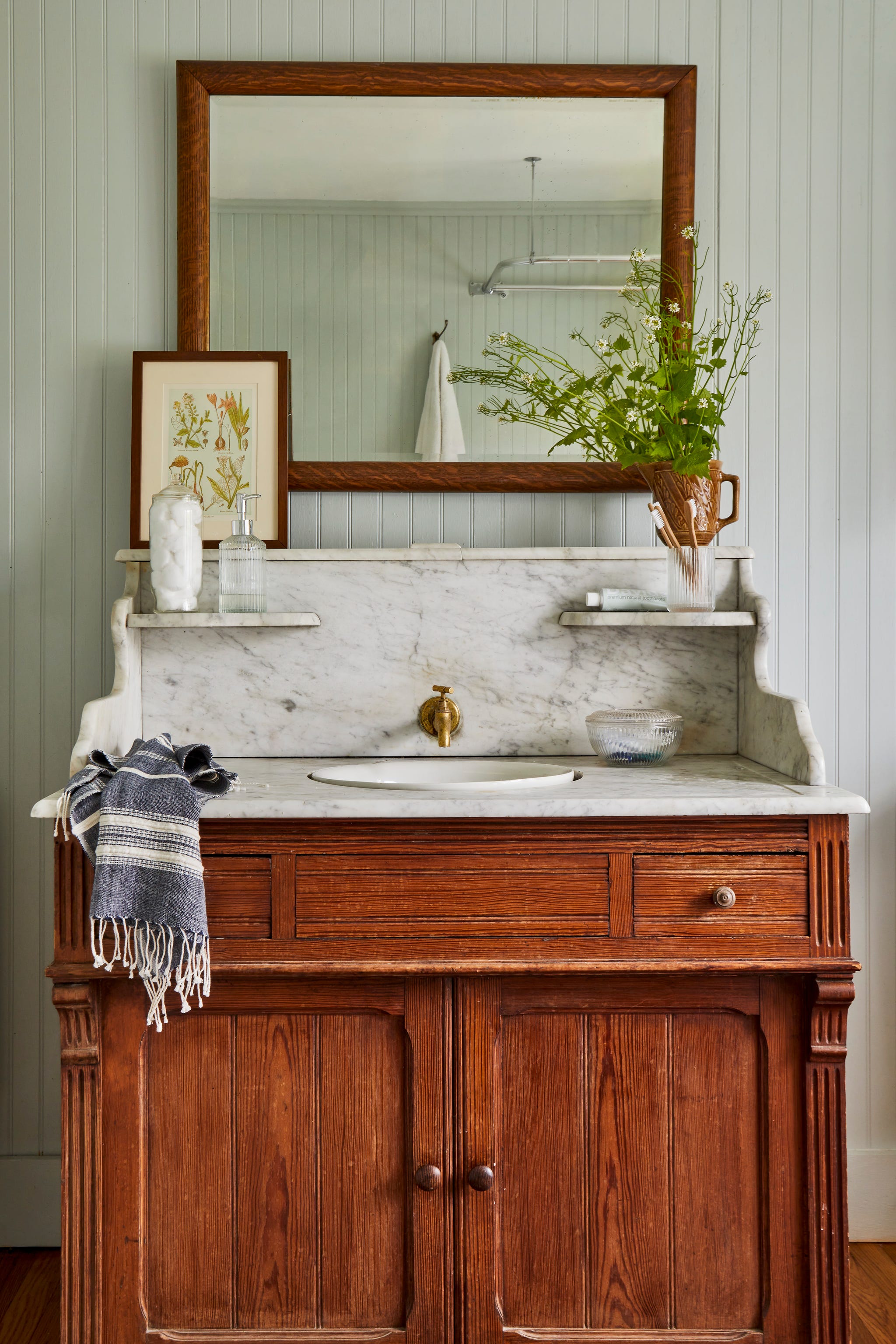 bathroom vanity with wood cabinets and marble sink and shelf with a mirror above it