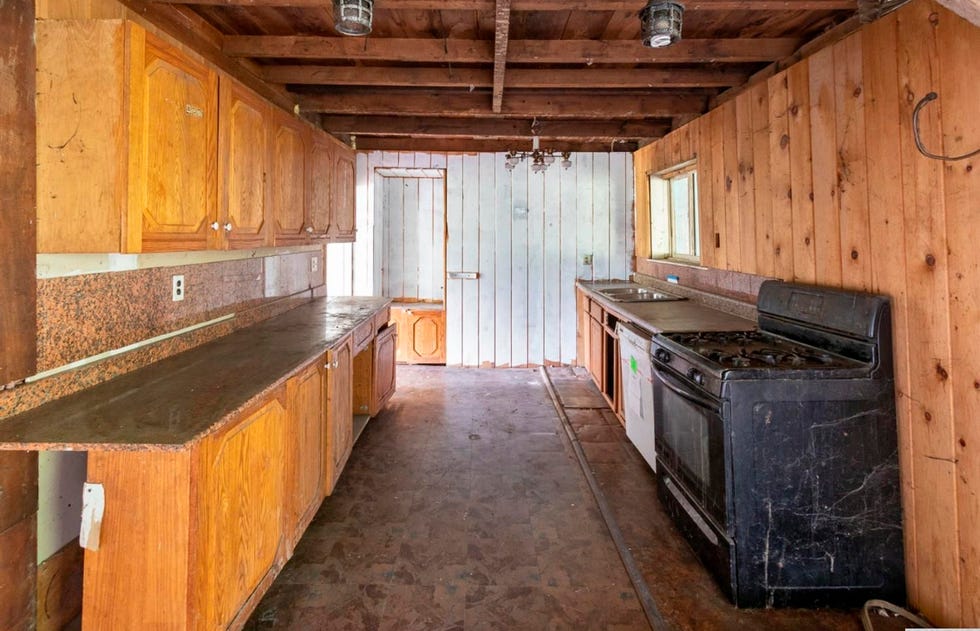 interior view of a rustic kitchen with wooden cabinets and an old stove