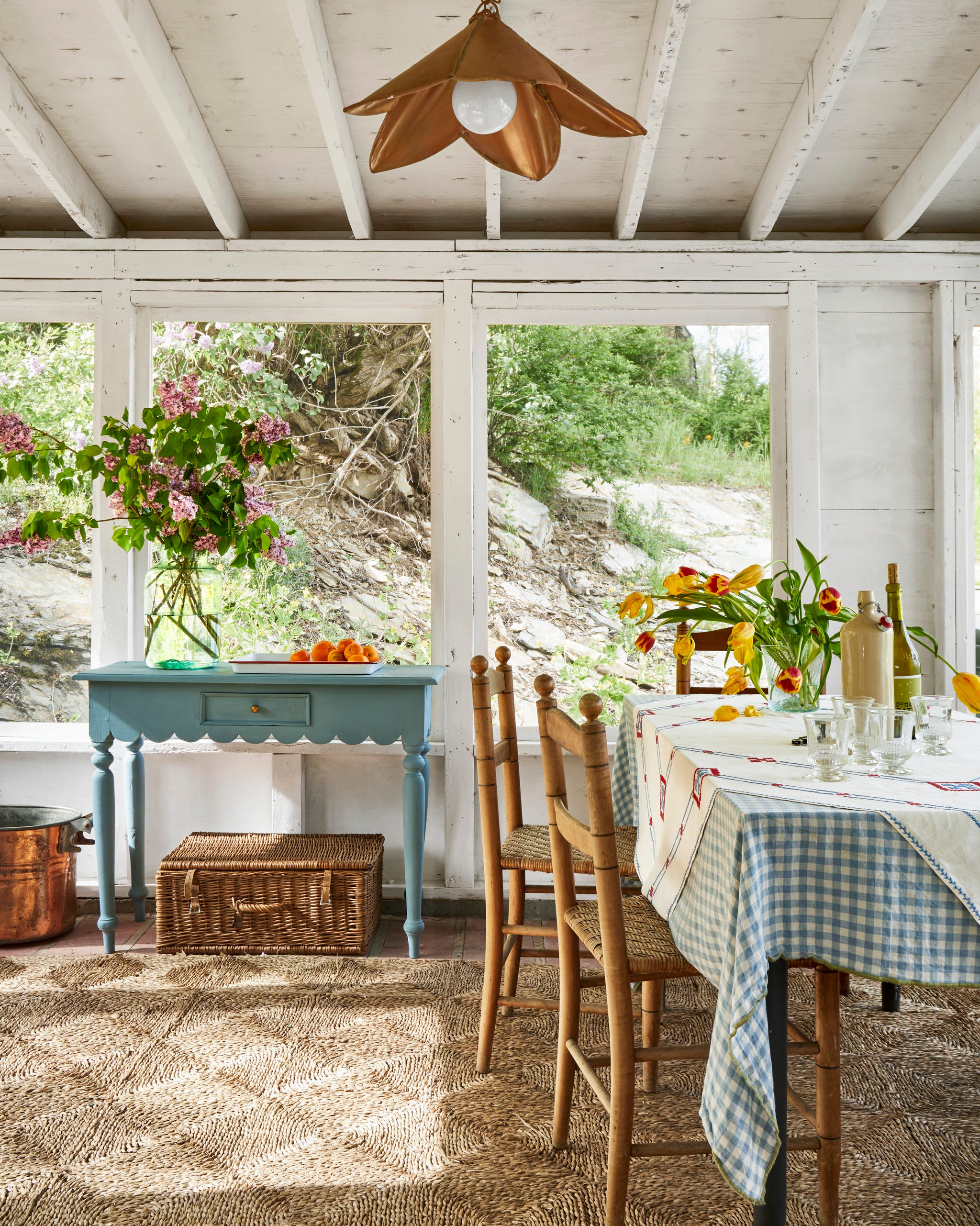 screened in porch with natural colored rug and dining table with gingham tablecloth
