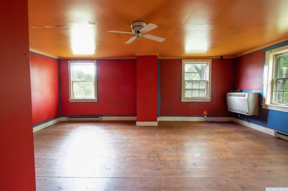a brightly colored room with an orange ceiling and red walls featuring two windows and a heater